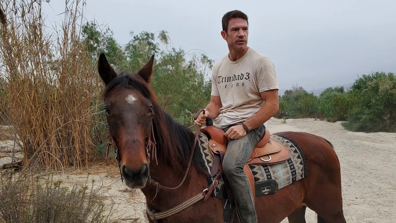A behind the scenes still of an actor wearing Trinidad3 apparel while on horseback from the upcoming film MVP